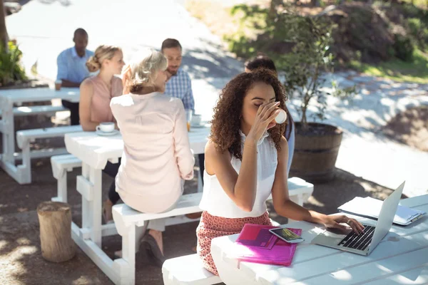 Hermosa mujer usando el ordenador portátil mientras toma café — Foto de Stock