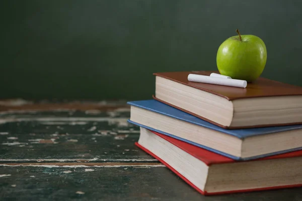 Manzana y tiza en la pila de libros — Foto de Stock