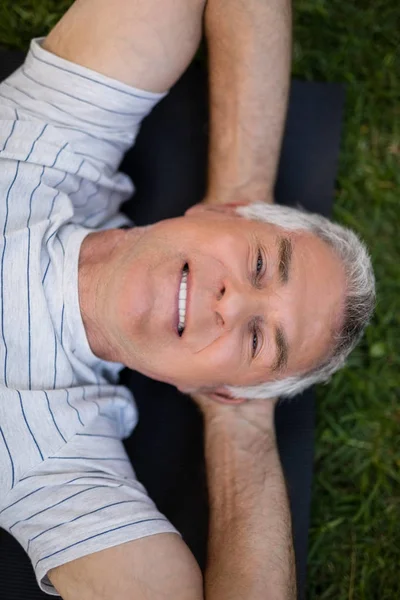 Senior homme se reposant tout en étant couché sur tapis d'exercice — Photo