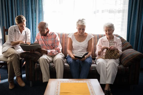 Vrouwelijke arts lezen boek door senior mensen — Stockfoto