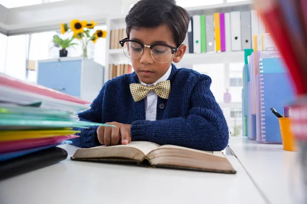 Empresario leyendo libro mientras está sentado en el escritorio — Foto de Stock