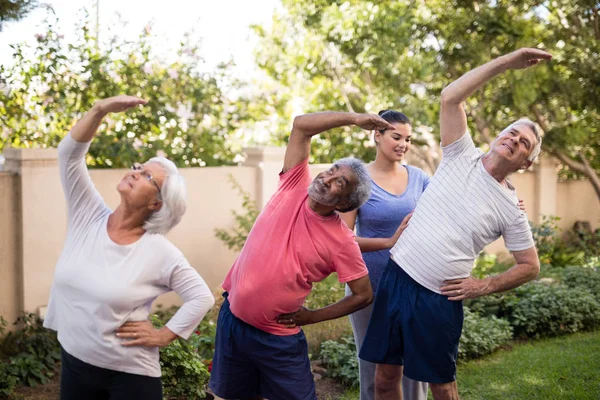 Formador orientando pessoas idosas durante o exercício — Fotografia de Stock