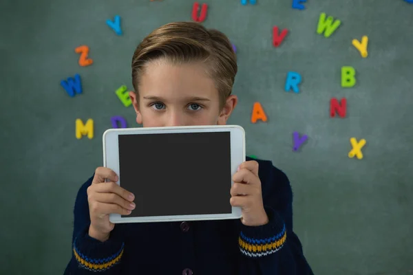 Schoolboy holding tablet against chalkboard — Stock Photo, Image