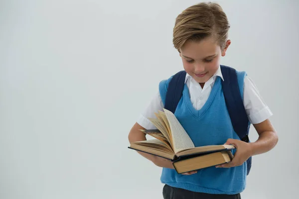 Schoolboy reading book against white background — Stock Photo, Image