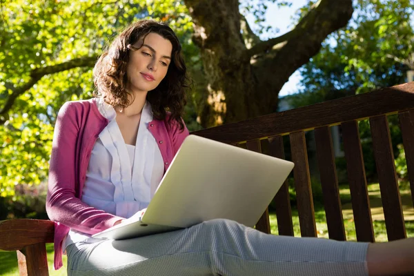 Frau sitzt auf Bank und benutzt Laptop — Stockfoto