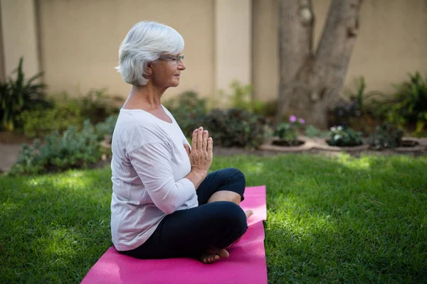 Mulher sênior meditando em posição de oração — Fotografia de Stock