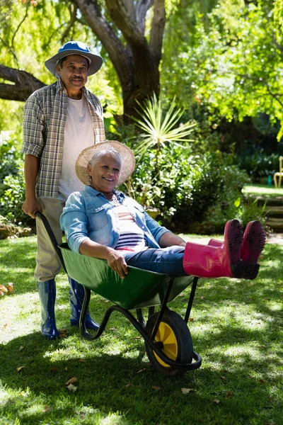 Uomo anziano dando donna cavalcare in carriola — Foto Stock