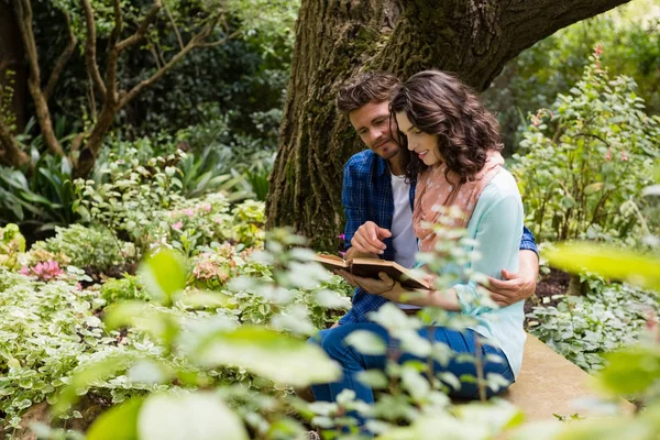 Casal romântico livro de leitura no banco no jardim — Fotografia de Stock