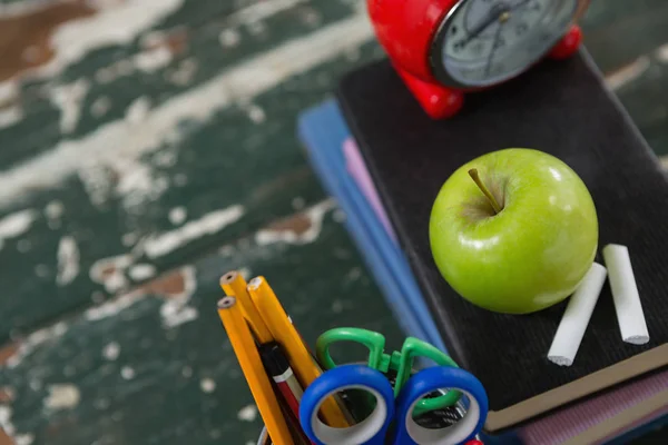 Reloj despertador, manzana y tiza en pila de libros —  Fotos de Stock