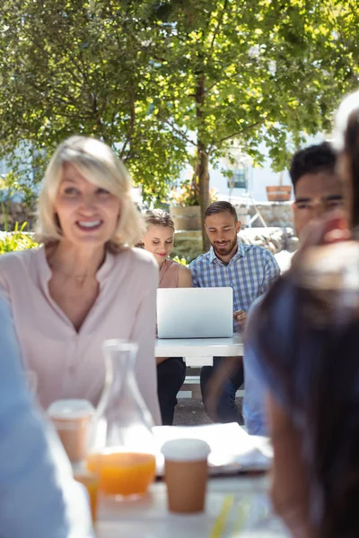 Amici che interagiscono tra loro e utilizzando il computer portatile — Foto Stock