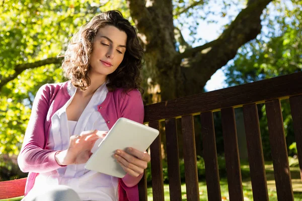 Woman sitting on bench and using tablet — Stock Photo, Image
