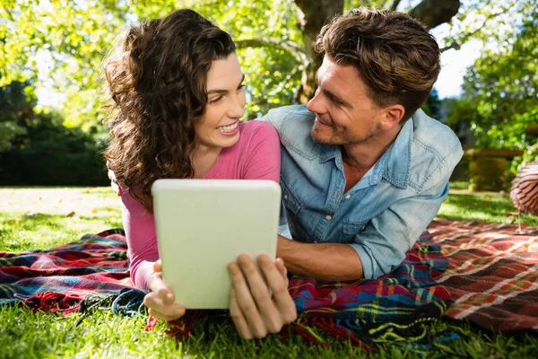 Paar liegt auf Picknickdecke und nutzt digitales Tablet — Stockfoto