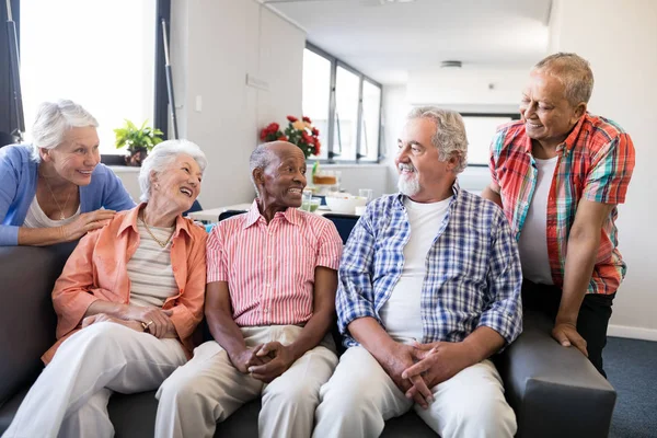 Усміхнені старші друзі слухають чоловіка — стокове фото