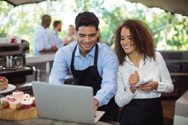 Manliga servitör och kvinnlig servitris med laptop — Stockfoto