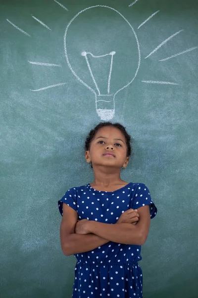 Girl with arms crossed standing by bulb — Stock Photo, Image