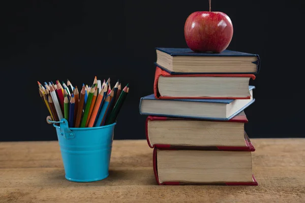 Apple on book stack with color pencils — Stock Photo, Image