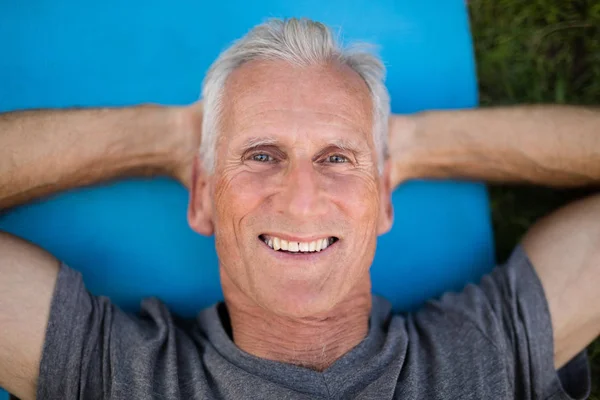 Senior man lying on exercise mat — Stock Photo, Image