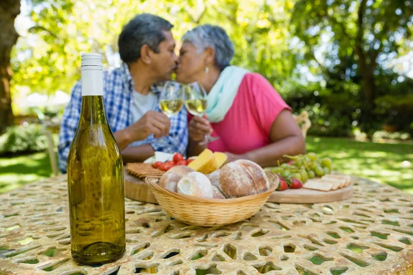 シニアのカップルがワインを飲みながらキス — ストック写真