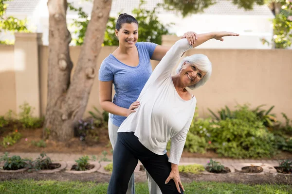 Sonriente entrenador ayudar a la mujer mayor — Foto de Stock