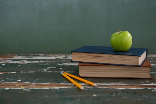 Manzana en la pila de libros con lápices — Foto de Stock