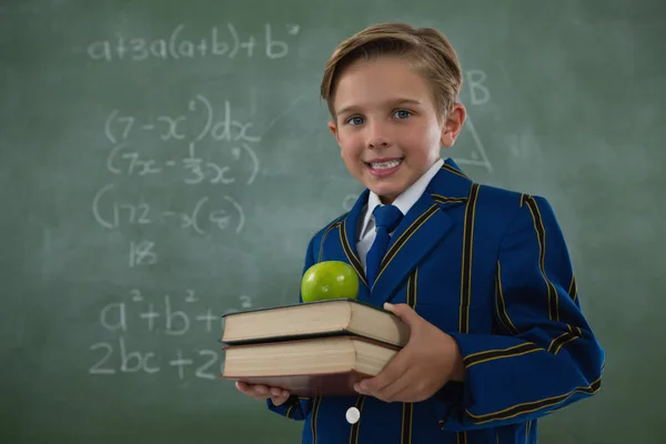 Школьник держит в руках стопку книг с яблоком — стоковое фото