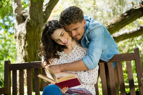 Романтична пара читає книгу на лавці в саду — стокове фото