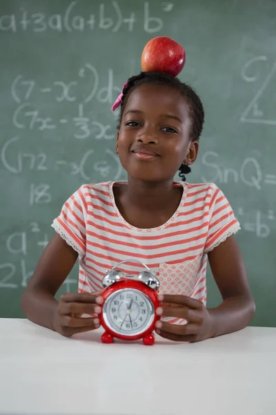 Schoolmeisje zit met rode appel op hoofd — Stockfoto