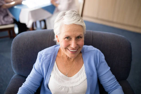 Lachende senior vrouw zittend op fauteuil — Stockfoto