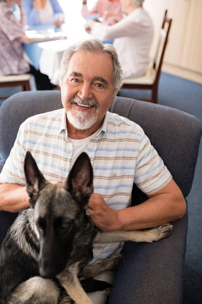Uomo anziano seduto con cucciolo sulla poltrona — Foto Stock