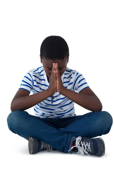 Мальчик сидит на полу и молится — стоковое фото