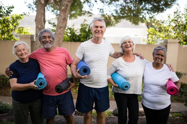 Rire amis aînés portant des tapis d'exercice — Photo