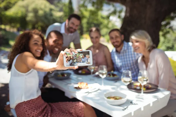 Amigos tomando selfie por teléfono mientras comen — Foto de Stock