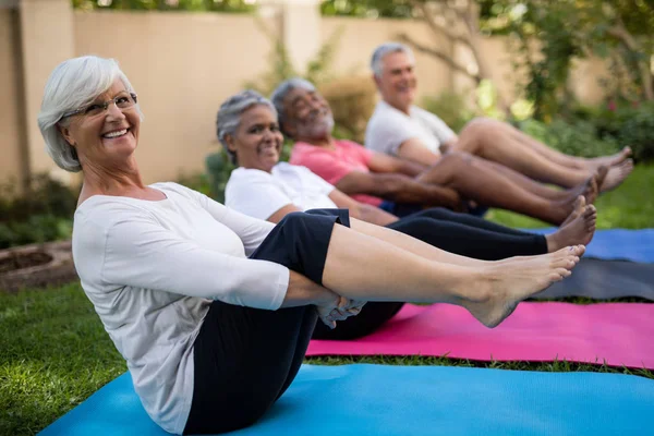Personas mayores haciendo ejercicio con los pies en alto — Foto de Stock
