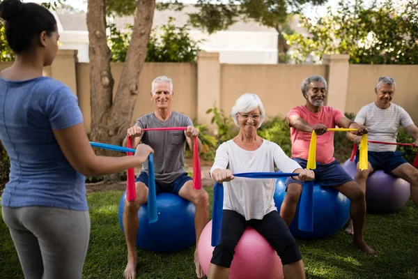 Formador orientando pessoas idosas durante o exercício — Fotografia de Stock