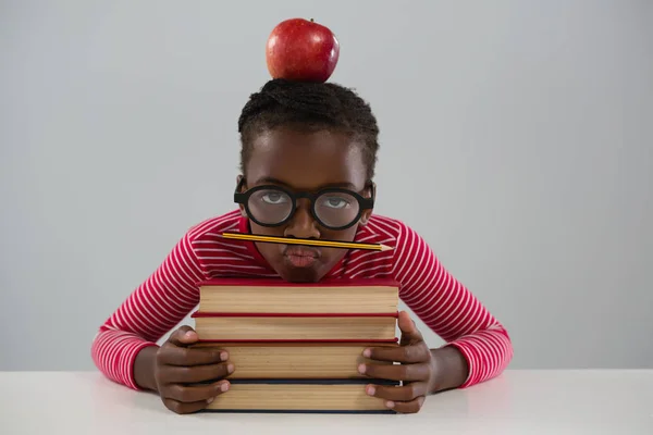 Colegiala apoyándose en la pila de libros — Foto de Stock