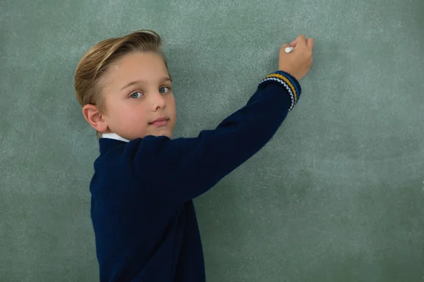 Schrijven met krijt op schoolbord schooljongen — Stockfoto