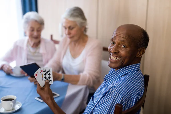 Улыбающийся мужчина играет в карты с друзьями — стоковое фото