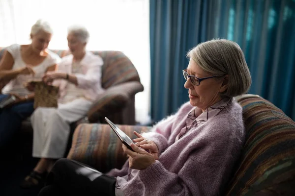 Senior kvinna använder surfplatta på fåtölj — Stockfoto