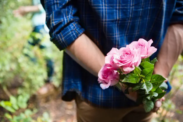 Hombre escondiendo flores detrás de atrás — Foto de Stock