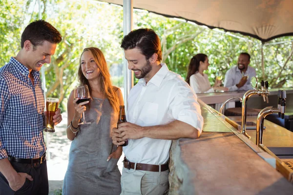 Amigos interactuando mientras toman alcohol — Foto de Stock