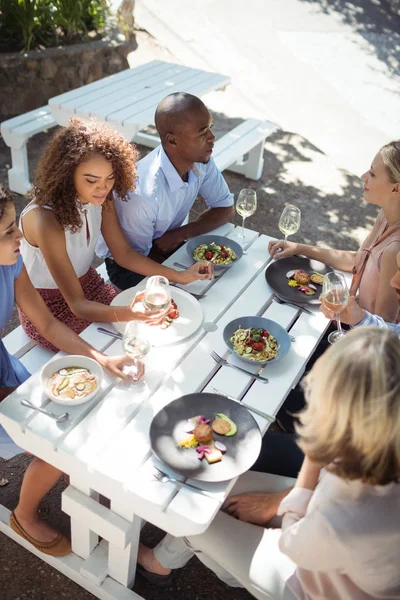 Amigos felices interactuando entre sí mientras comen — Foto de Stock