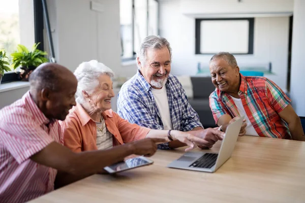 Щасливі люди похилого віку вказують на ноутбук — стокове фото