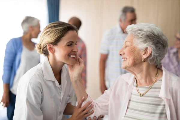 Mujer mayor tocando sonriente médico femenino —  Fotos de Stock