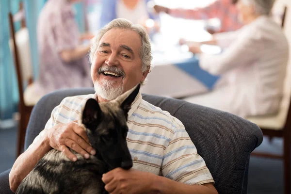 Uomo anziano seduto con cucciolo sulla sedia — Foto Stock