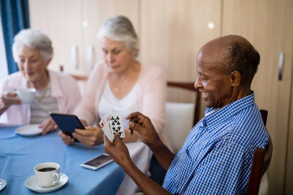 Старший игрок в карты с друзьями — стоковое фото