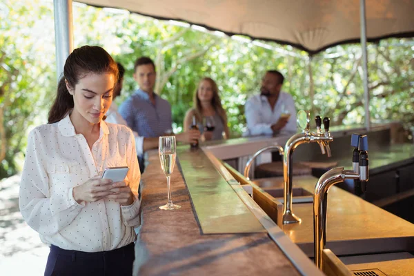 Woman using phone while having champagne — Stock Photo, Image