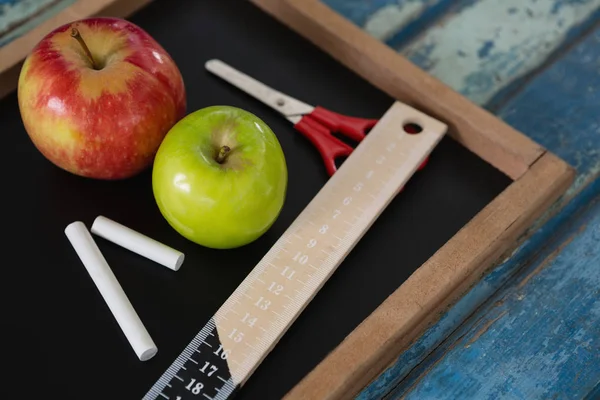 Koulutarvikkeet ja liuskekivi puinen pöytä — kuvapankkivalokuva