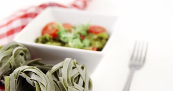 Fresh spinach fettuccine noodles and bowl of salad on table — Stock Video