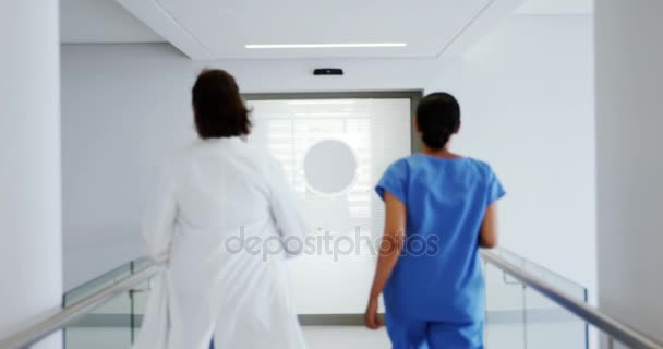Arts en verpleegkundige uitgevoerd in doorgang van ziekenhuis — Stockvideo
