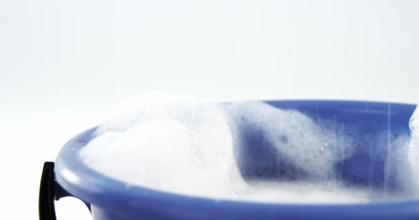 Чистящая губка падает в ведро с мылом — стоковое видео